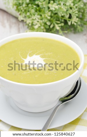 bowl of green pea soup with ginger and cream in a white bowl