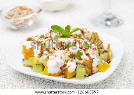 fruit salad with nuts, yogurt and mint garnished with yogurt and nuts, closeup