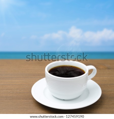cup of coffee with steam on a wooden table on a background of blue sky