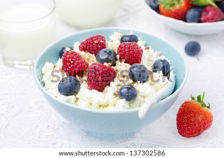 bowl of cottage cheese with berries, honey and nuts, fresh berries and milk for breakfast, horizontal closeup