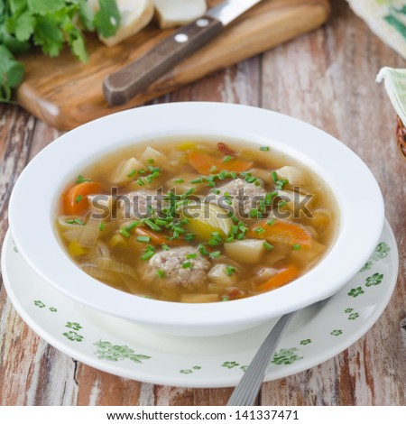 Plate of vegetable soup with meatballs on the wooden table closeup