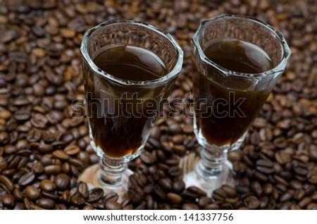 two shot glasses of coffee liqueur on the background of coffee beans, horizontal