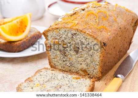 orange cake with poppy seeds, dried apricots, walnuts and honey glaze on a wooden board horizontal closeup