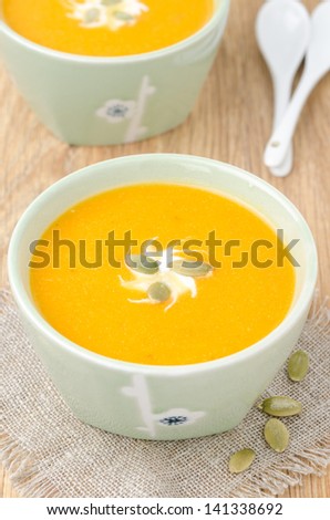 bowl of pumpkin soup with ginger, yogurt and pumpkin seeds, top view