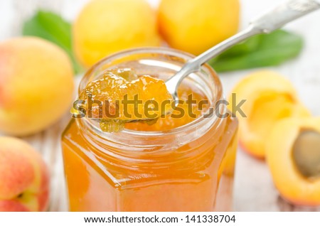 apricot marmalade in a spoon close-up and fresh apricots the background