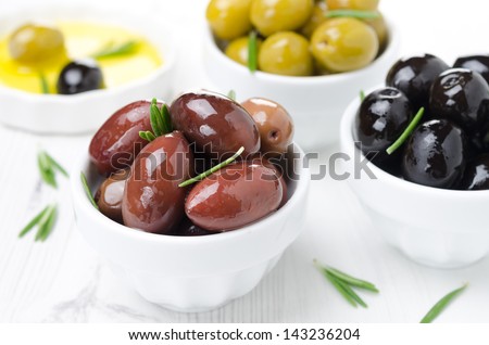 kalamata olives, black and green olives, rosemary and olive oil on a white background