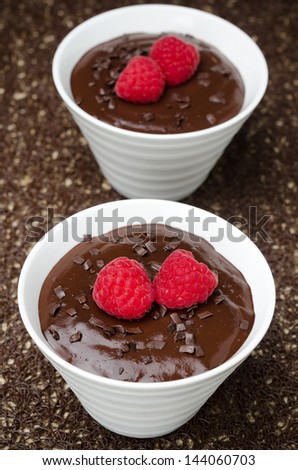 two bowls of chocolate mousse and fresh raspberries, top view, vertical
