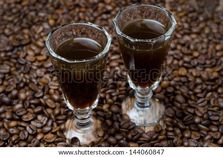 two shot glasses of coffee liqueur on the background of coffee beans, selective focus