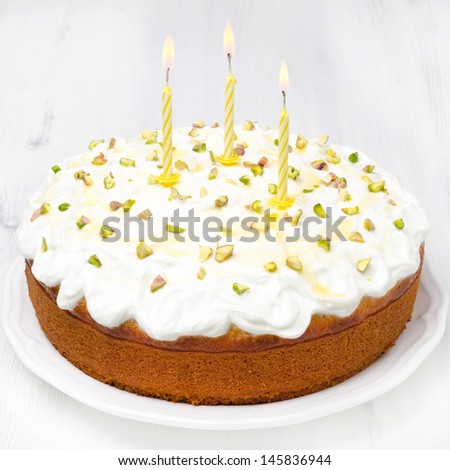 orange cake with Greek yogurt, honey and pistachios, decorated with burning candles, close-up