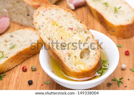 piece of baguette in a fragrant olive oil and spices on a wooden board, close-up