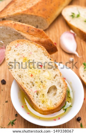 piece of baguette in a fragrant olive oil, spices and garlic on a wooden board, close-up, vertical