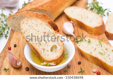piece of baguette in a fragrant olive oil, spices and garlic on a wooden board, close-up