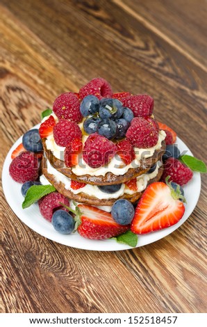 Pancake cake with whipped cream and fresh berries on the wooden table vertical top view, closeup