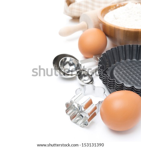 cookie cutters, measuring spoons, eggs and flour for baking isolated on white
