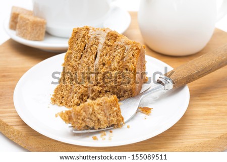 piece of honey cake on a plate and fork on wooden board, close-up