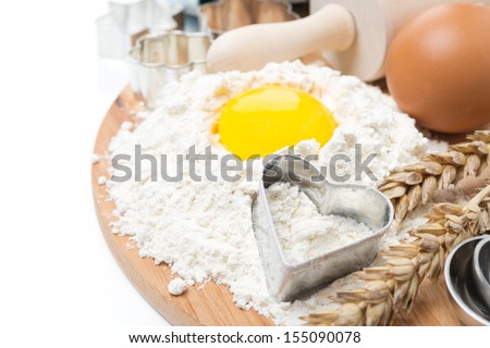 flour, eggs, rolling pin and baking forms on wooden board isolated on white