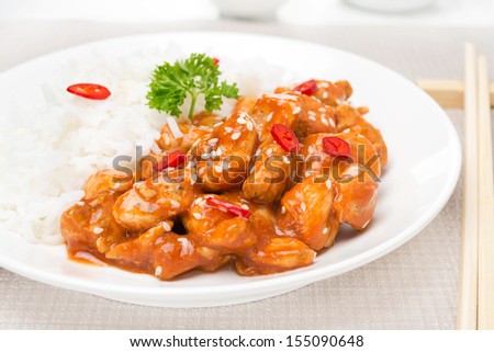chicken fillet in tomato sauce with sesame seeds and rice close-up, horizontal
