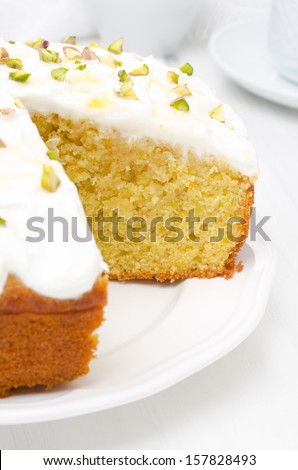 orange cake with Greek yogurt, honey and pistachios in a cut, close-up, vertical