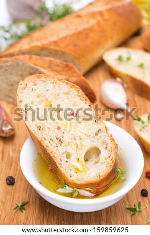piece of baguette in a fragrant olive oil, spices and garlic on a wooden board, vertical close-up