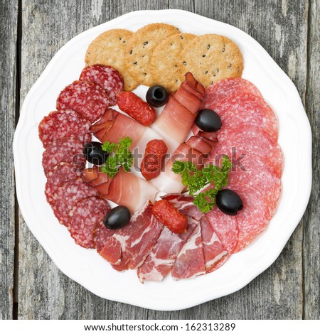 plate of meat delicacies and crackers, top view, close-up