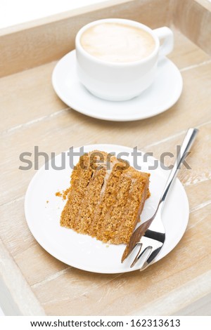 piece of honey cake and cup of cappuccino on a wooden tray, top view, vertical