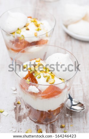 dessert with canned peaches, whipped cream, meringue and pistachios, vertical