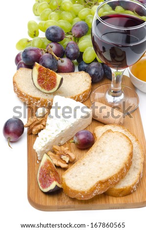 snacks - cheese, bread, figs, grapes, nuts and red wine on a wooden board isolated on white