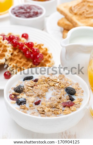 muesli with milk, waffles with berries, toast and jam for breakfast, vertical