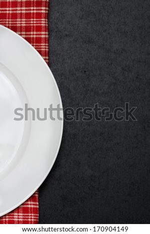 part of the empty plate on a checkered napkin and black background for your text, vertical