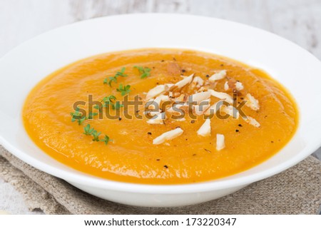 carrot soup with almonds and watercress on white wooden table, close-up, horizontal