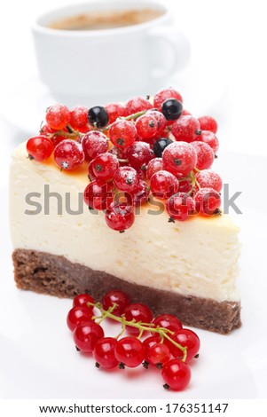 piece of cheesecake with red and black currants and a cup of coffee