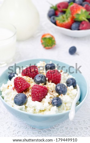 bowl of cottage cheese with berries, honey and nuts, fresh berries and milk for breakfast, vertical