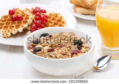 muesli, waffles with berries and orange juice for breakfast, close-up