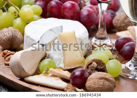 Camembert, a glass of red wine, grapes and crackers, close-up, horizontal