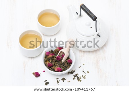 green tea with rosebuds, cups and teapot on white table, top view, horizontal