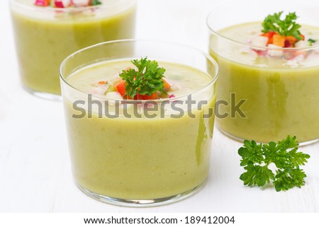 green soup with fresh vegetables in glasses, close-up, horizontal