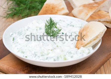 yoghurt sauce tzatziki with herbs, cucumber and garlic and pita bread, close-up, horizontal