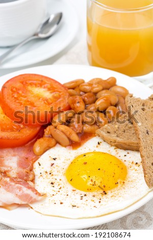 English breakfast with fried eggs, bacon, beans, toasts, close-up
