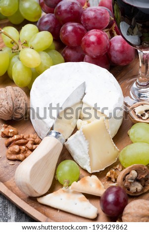 Camembert, a glass of red wine, grapes and crackers, vertical