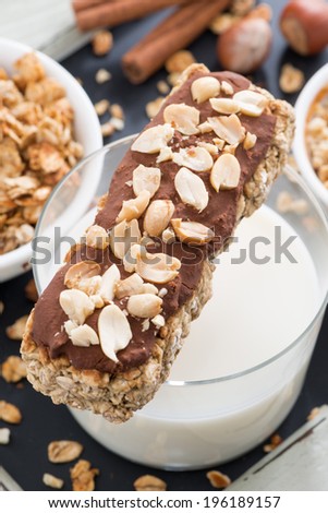oat bar with chocolate and nuts, a glass of milk, top view, vertical
