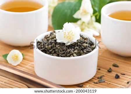dry green tea with jasmine and cups of tea, close-up