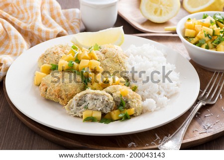 fish cakes with mango salsa and rice on a plate