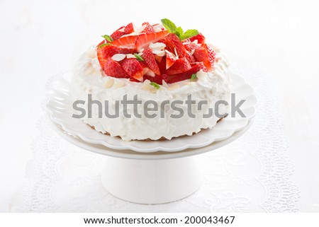 cake with whipped cream and strawberries on a stand, close-up
