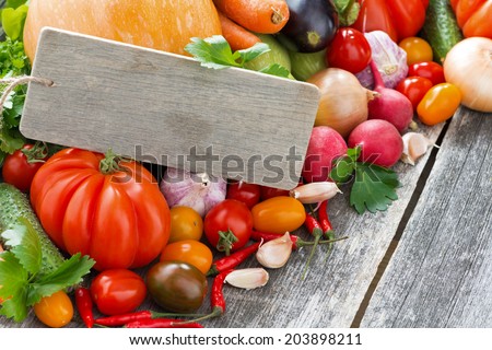 Assorted fresh seasonal vegetables and a wooden nameplate, horizontal, close-up