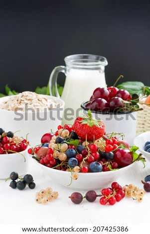 fresh berries, fruit, cereal and milk for breakfast. black background for text, vertical