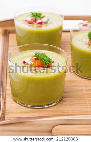 green soup with fresh vegetables on a wooden tray, vertical
