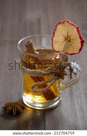 spiced apple cider in glass mug on a wooden table, vertical, close-up
