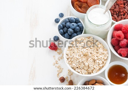 cereal and various delicious ingredients for breakfast and white wooden background, top view