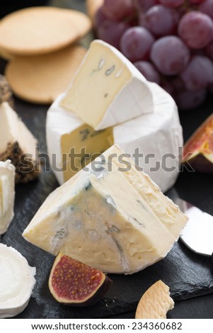 delicacy soft cheeses, fruit and crackers - snacks for wine, close-up, vertical