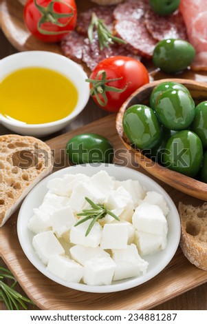 antipasti platter - fresh feta cheese, deli meats, olives and ciabatta, top view, vertical